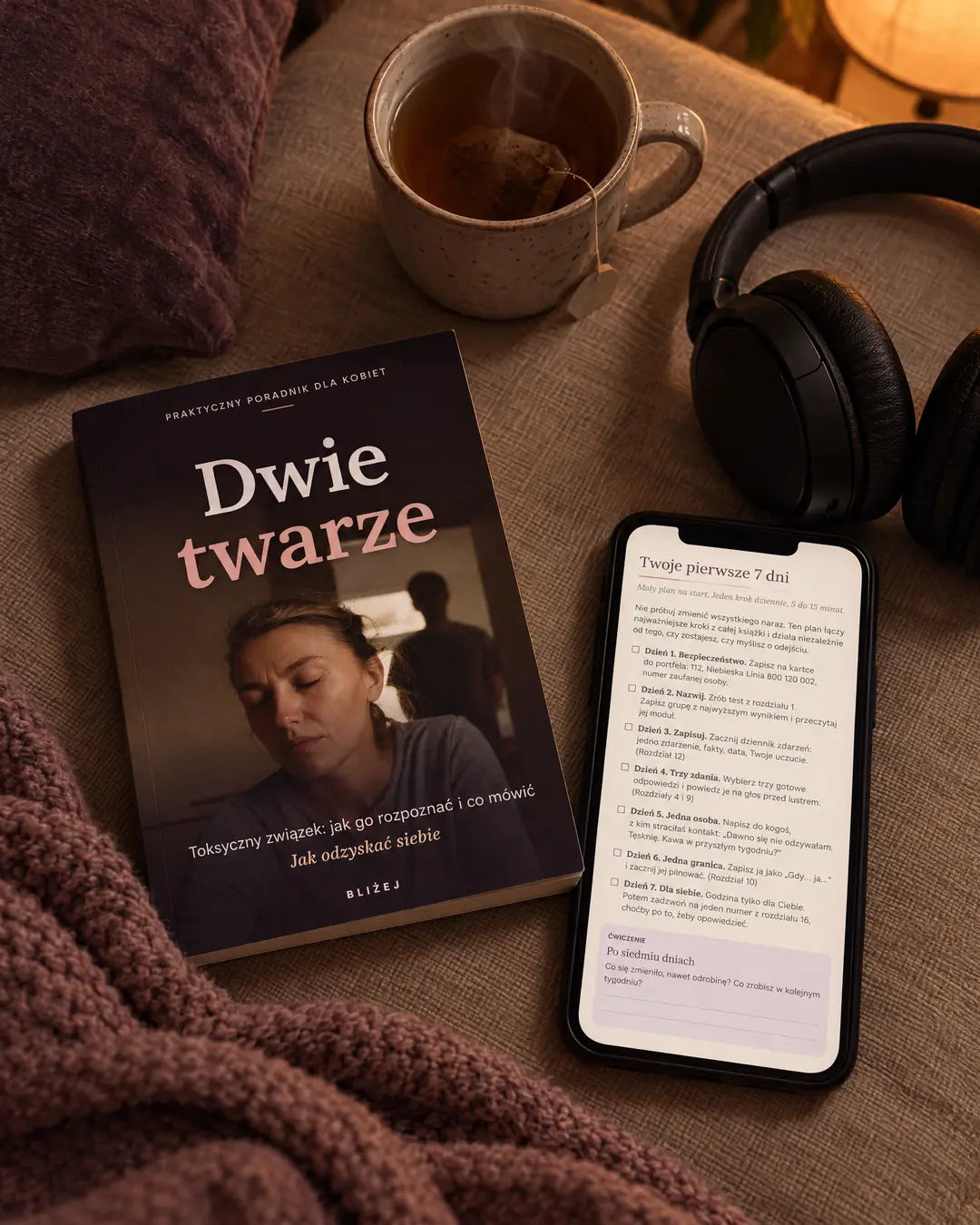 Okładka e-booka i telefon z otwartym PDF na kanapie, słuchawki i herbata